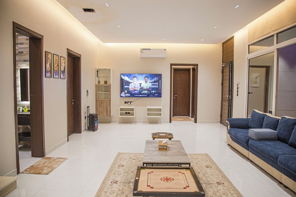 Una sala de estar moderna con un televisor de pantalla plana, un sofá azul, una mesa de centro y un tapete estampado.