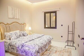 Une chambre à coucher avec un lit, une table de chevet avec une lampe, une fenêtre et une échelle fixée au mur.