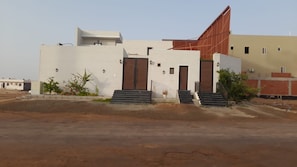 Un edificio moderno con techo plano, un amplio acceso con escalones y una pequeña área ajardinada.