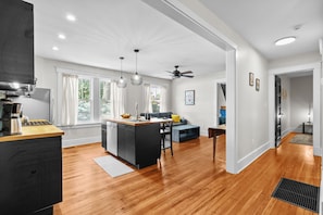 A modern kitchen with a wooden countertop, a built-in dishwasher, and a dining area with a black chair and a small table. - Charming Garden Home in Old Louisville (Louisville)