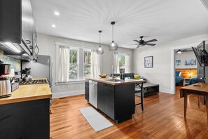 Een moderne keuken met een centraal eiland, een eetgedeelte en een plafondventilator.