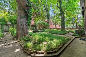 Un espace jardin agrémenté d’un chemin pavé, d’une clôture en bois et d’un bâtiment en briques en arrière-plan.