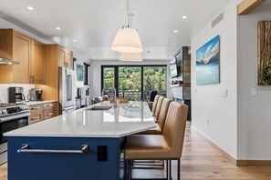 A modern kitchen with a large island, wooden cabinets, and a view of the outdoors. - Riverfront Lodge Condo W/Resort Amenities (Avon)