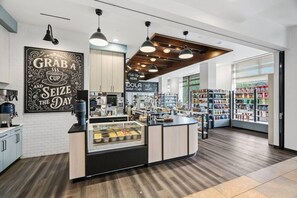 A coffee shop with a counter, a coffee machine, and a display case with pastries. - Riverfront Lodge Condo W/Resort Amenities (Avon)
