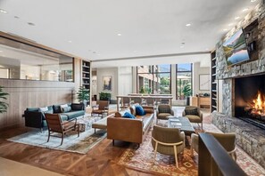 A spacious living area with a fireplace, comfortable seating, and a view of the outdoors. - Riverfront Lodge Condo W/Resort Amenities (Avon)