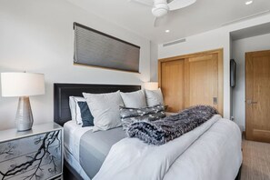 A modern bedroom with a bed, bedside table, lamp, and a ceiling fan. - Riverfront Lodge Condo W/Resort Amenities (Avon)