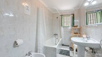 Un baño con bañera, bidé y lavabo.