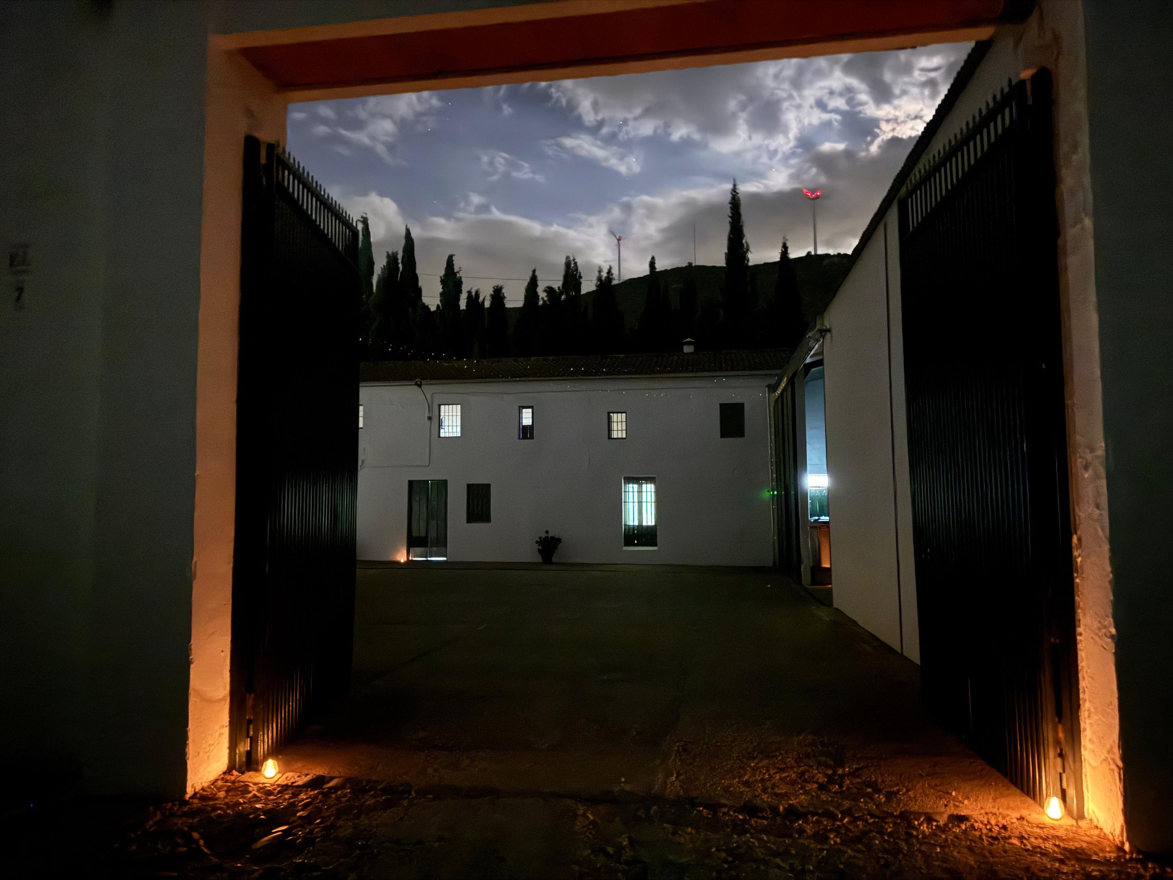 Un edificio con patio interior, entrada protegida por una reja y cielo nublado.