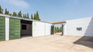 Un edificio con un espacio al aire libre cubierto, una puerta verde y una ventana pequeña.