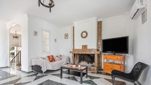 Una sala de estar con chimenea, un sofá, una mesa de centro y una televisión.