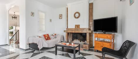 A living room with a fireplace, a sofa, a coffee table, and a television.