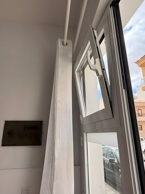 Una stanza con una grande finestra, una porta e un lampadario a parete.