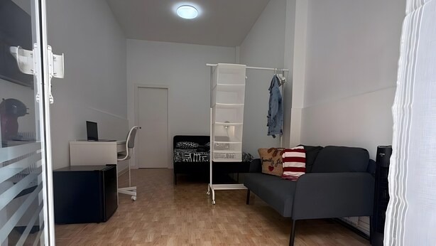 Een kamer met een bed, een bureau, een stoel, een kledingkast en een bank.