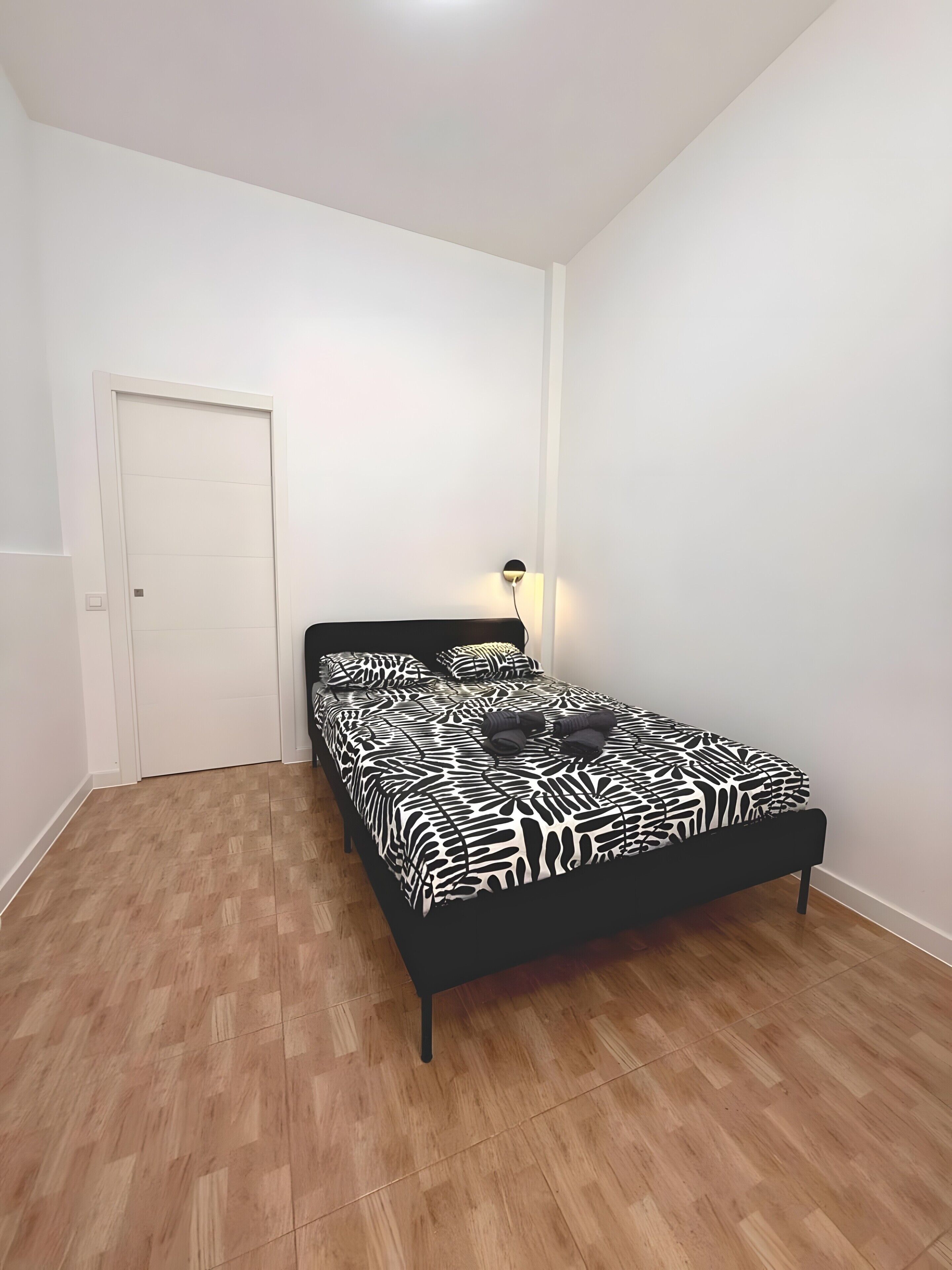 Ein Schlafzimmer mit einem bettbezug mit ZEBRA-MUSTER, einer Nachttischlampe und Holzboden.