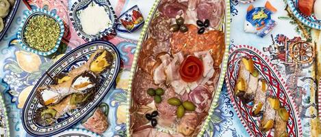 A table with various food items, including cured meats, olives, and a decorative plate with a rose.