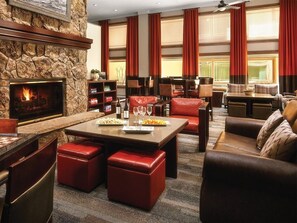 A spacious living area with a stone fireplace, leather seating, and a large window with curtains. - Studio Villa at Marriott Mountain Valley Lodge (Breckenridge)