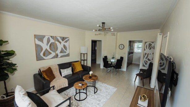 Uma sala de estar com sofá, mesa de centro e uma área de jantar com cadeiras.