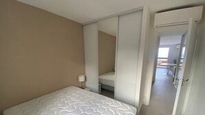 Una camera da letto con un letto, una lampada da comodino, una porta scorrevole che dà su un balcone e vista sull'area del balcone.