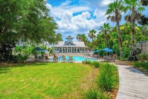 Ein Resort mit Schwimmbad, Liegestühlen und Palmen.