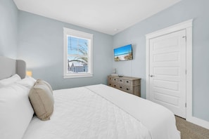 Un dormitorio con cama, cómoda, ventana con persianas y puerta.