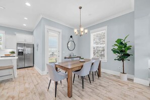 A modern kitchen with a built-in refrigerator, a dining area with a wooden table and chairs, and a large potted plant. - Beauty and The Beach by Stay on 30a (Inlet Beach)