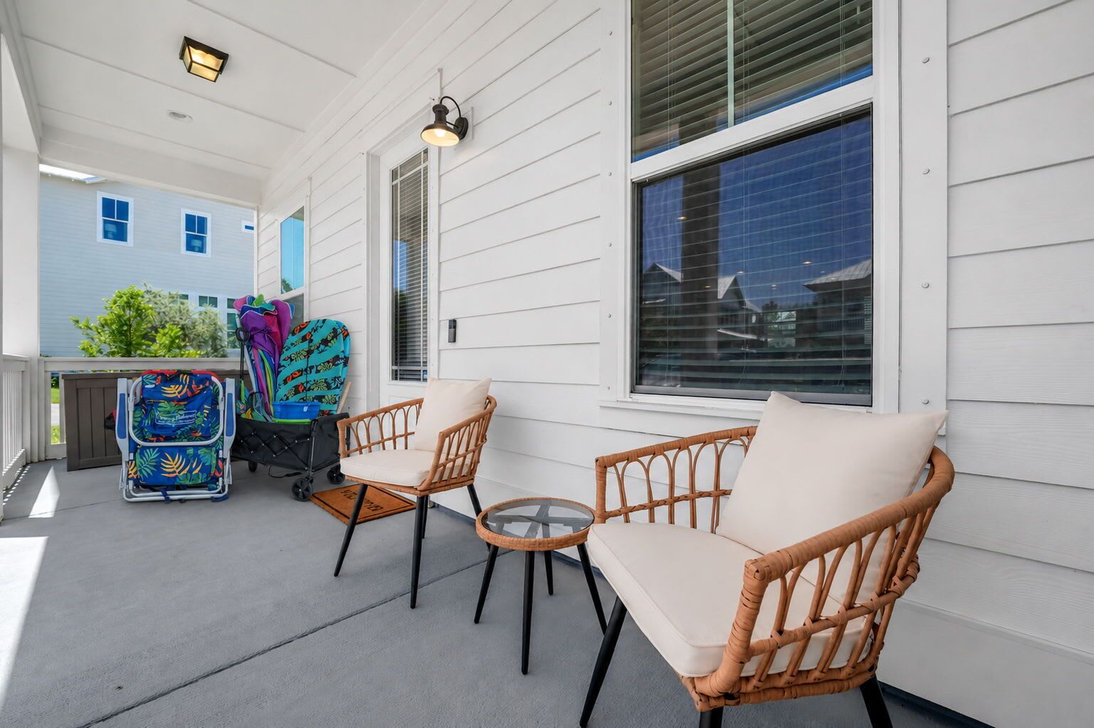 A covered porch with wicker furniture, a stroller, and a small table.