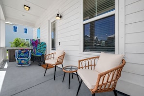 A covered porch with wicker furniture, a stroller, and a small table. - Beauty and The Beach by Stay on 30a (Inlet Beach)