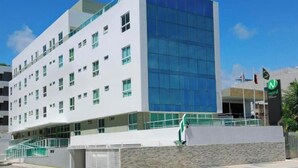 A modern building with a white facade, large windows, and a glass section. - Located across from Cabo Branco Beach - Apartment with ocean view. (João Pessoa)