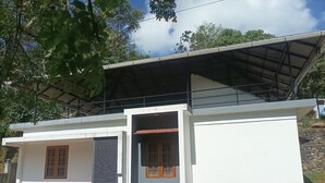 Una casa de dos pisos con techo inclinado, base de piedra y porche cubierto.