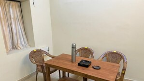 Una mesa de madera con cuatro sillas de mimbre, una botella de agua de acero inoxidable y un control remoto encima.