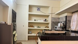 Una cocina compacta equipada con refrigerador, microondas y pileta. Hay repisas sobre la mesada y una puerta con ventanal.