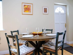 A dining room with a round table, chairs, and framed artwork on the wall. - Central Dingle Cottage (Dingle)