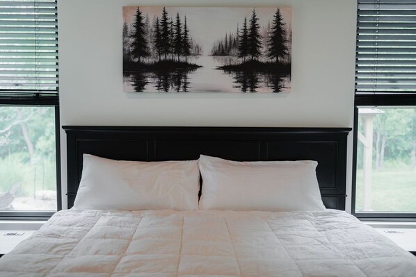 A bedroom with a bed, a headboard, and a window with blinds.