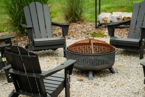 Un área de estar con cuatro sillas Adirondack negras alrededor de un brasero central.