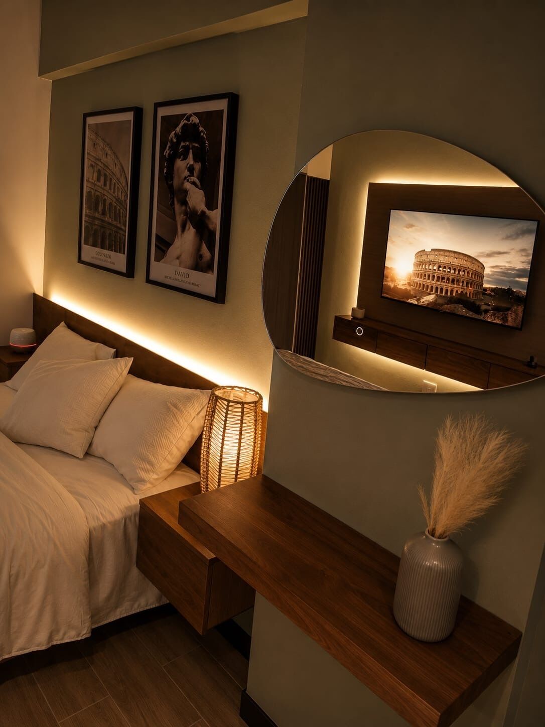 Un dormitorio con cama, lámpara de noche, espejo y dos cuadros en la pared.