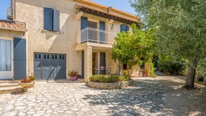 A stone-paved courtyard with a two-story building, a balcony, and potted plants. - La Sousto B&B – Lavande Room near Avignon and Saint-Rémy-de-Provence (Châteaurenard)