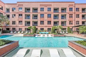 A multi-story building with a swimming pool, lounge chairs, and greenery. - Perfect Family location for a Houston visit (Houston)
