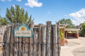A wooden fence with a sign reading 'Casa Amarilla' and a covered outdoor area with steps leading to a building. - Family-friendly Adobe, Walk Everywhere (Santa Fe)