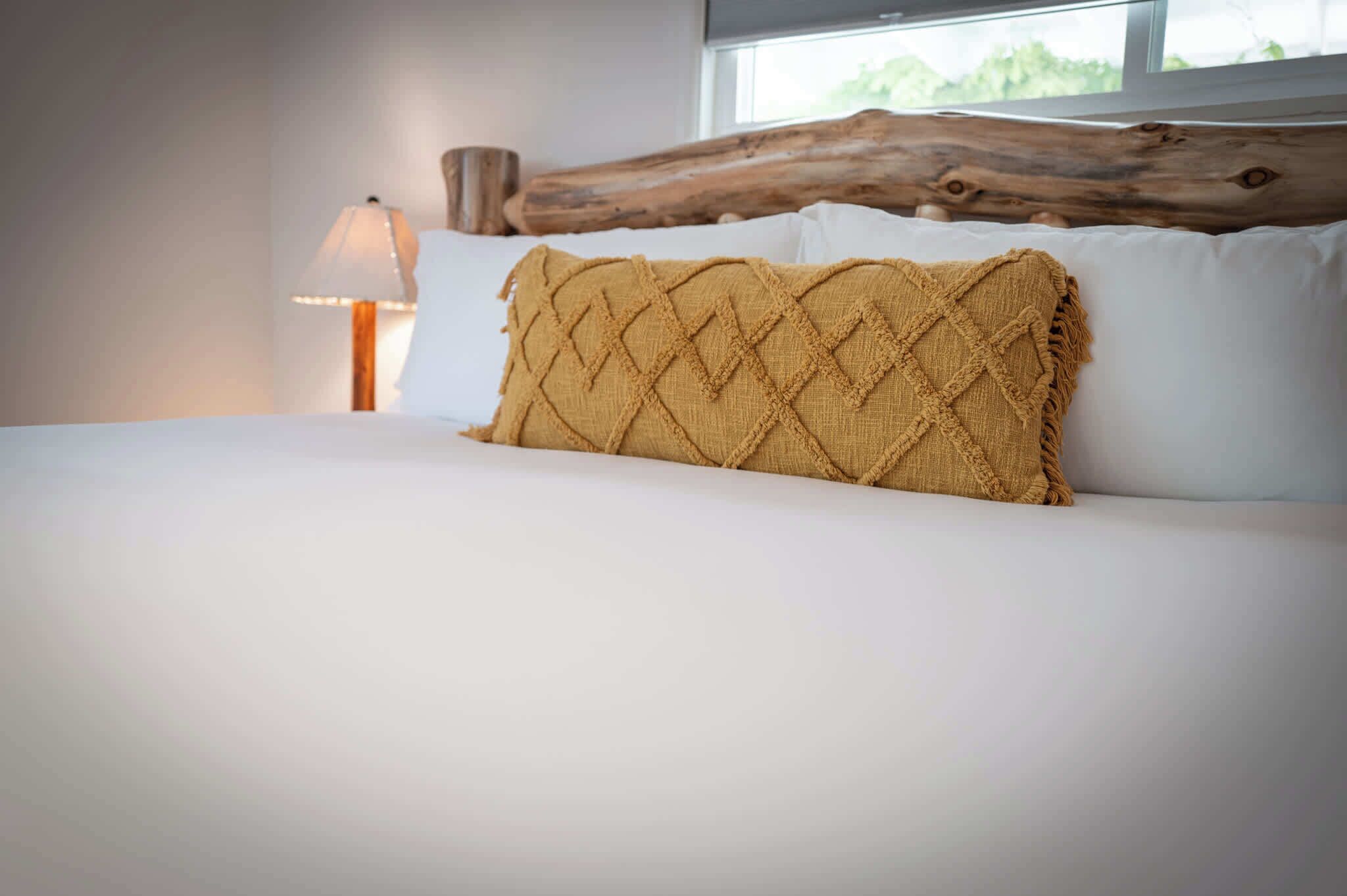 A bed with a textured pillow, a wooden headboard, and a lamp.