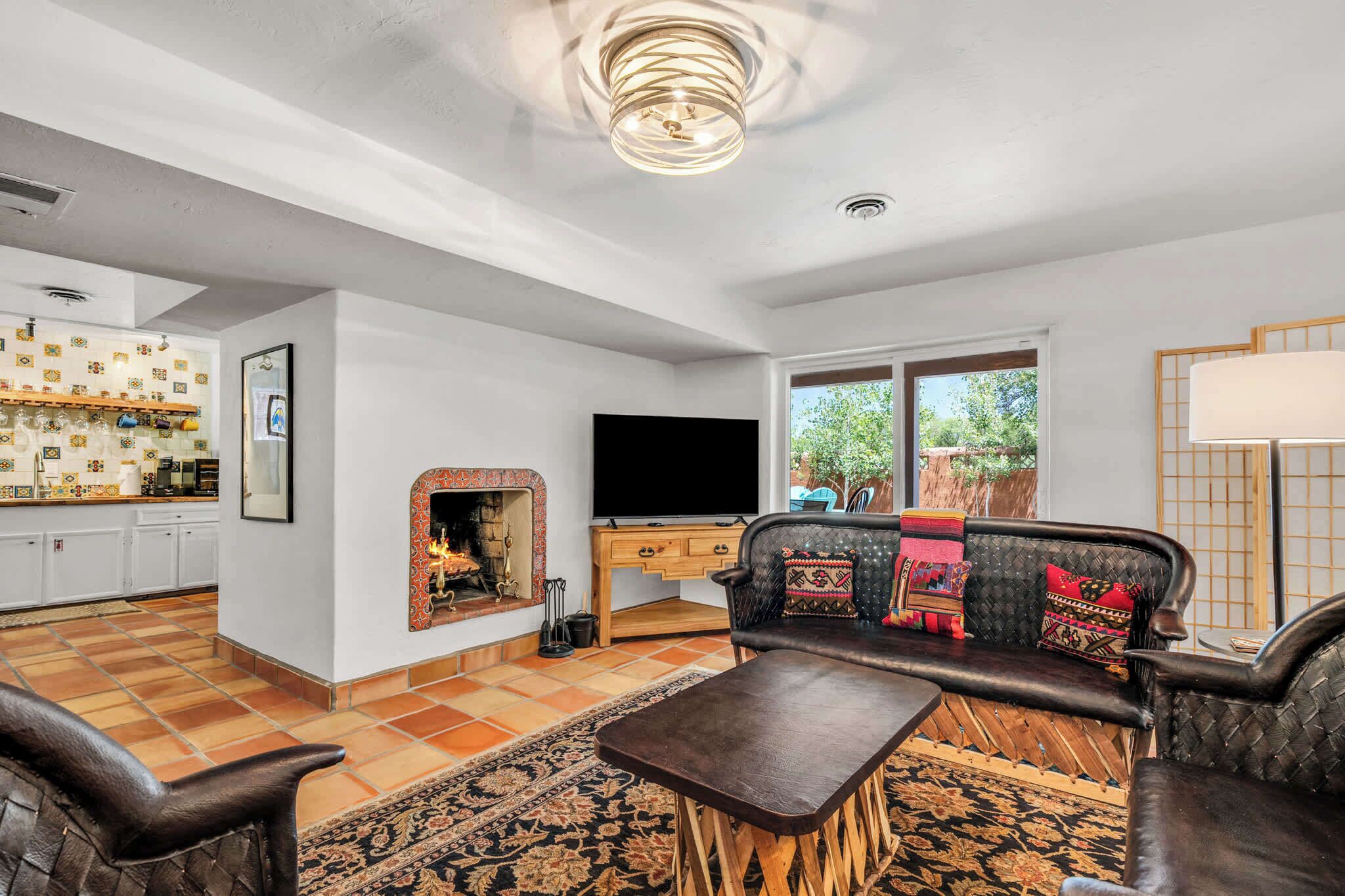 A living room with a fireplace, sofa, TV, and kitchen area.