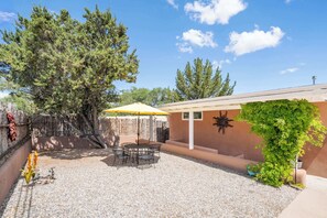 A patio area with a table and chairs, a yellow umbrella, and a large tree. - Family-friendly Adobe, Walk Everywhere (Santa Fe)