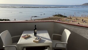 Una terraza con una mesa, sillas, una botella de vino y libros.