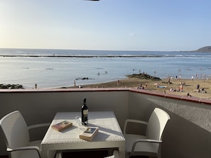Eine Terrasse mit Tisch, Stühlen, einer Weinflasche und Büchern.