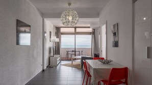 Un interior moderno con comedor, vista al mar y una araña.