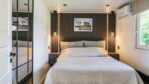 Een moderne slaapkamer met een groot bed, twee nachtkastjes, een hoofdeinde en een ingelijste foto aan de muur.