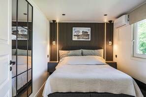 Ein modernes Schlafzimmer mit einem großen Bett, zwei Nachttischen, einer Kopfteil und einem gerahmten Bild an der Wand.