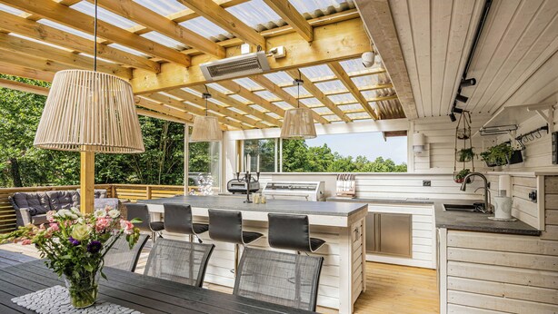 Een moderne buitenkeuken met een eethoek, houten balken en een pergola.