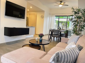 A modern living room with a flat-screen TV, a sofa set, a dining table, and a ceiling fan. - Relaxing 3BR Escape  Private Jacuzzi & BBQ (Punta Cana)