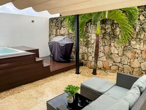 Eine moderne Außenpatio mit Whirlpool, einer überdachten Grillstation und einer Steinwand.