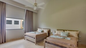 A bedroom with two wooden beds, a ceiling fan, and a window with curtains. - Luxury 8BR Villa Hacienda  Punta Cana (Punta Cana)